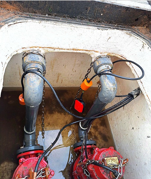 View into a sump pit showing pumps, discharge pipework, floats and cables