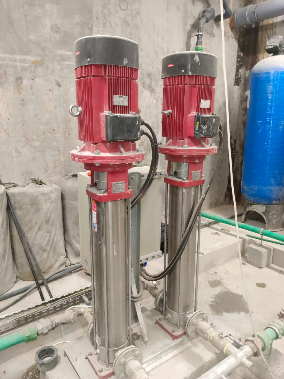 Installed twin vertical pump system beside a blue pressure vessel